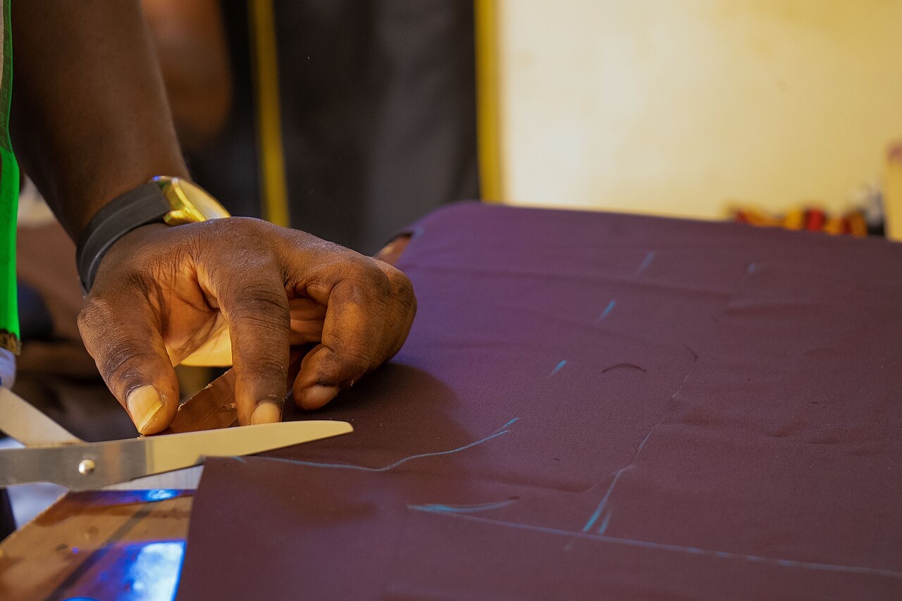 A tailor cutting cloth by hand along chalk lines